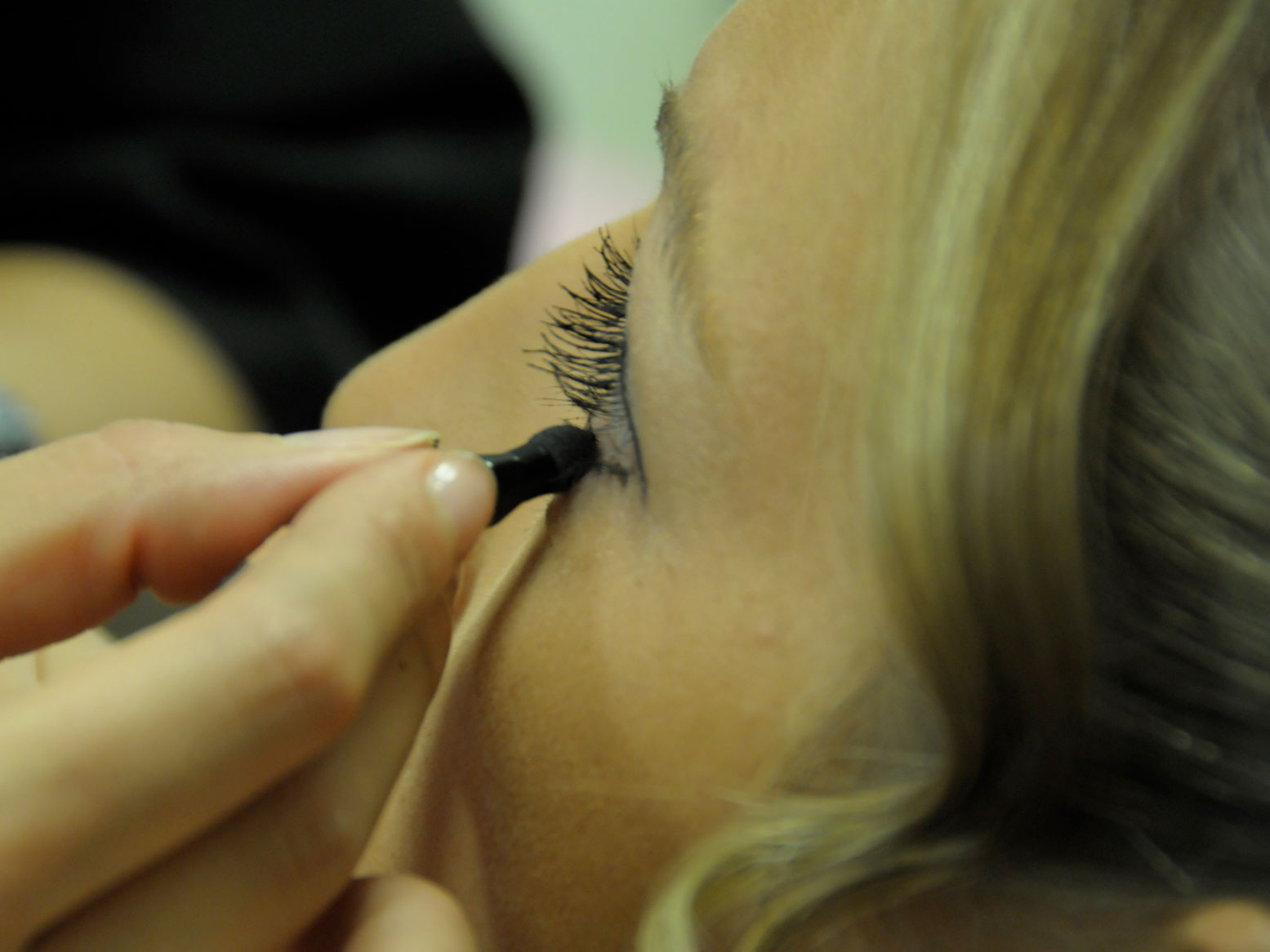 Der Braut wird beim Friseur der Lidschatten aufgetragen