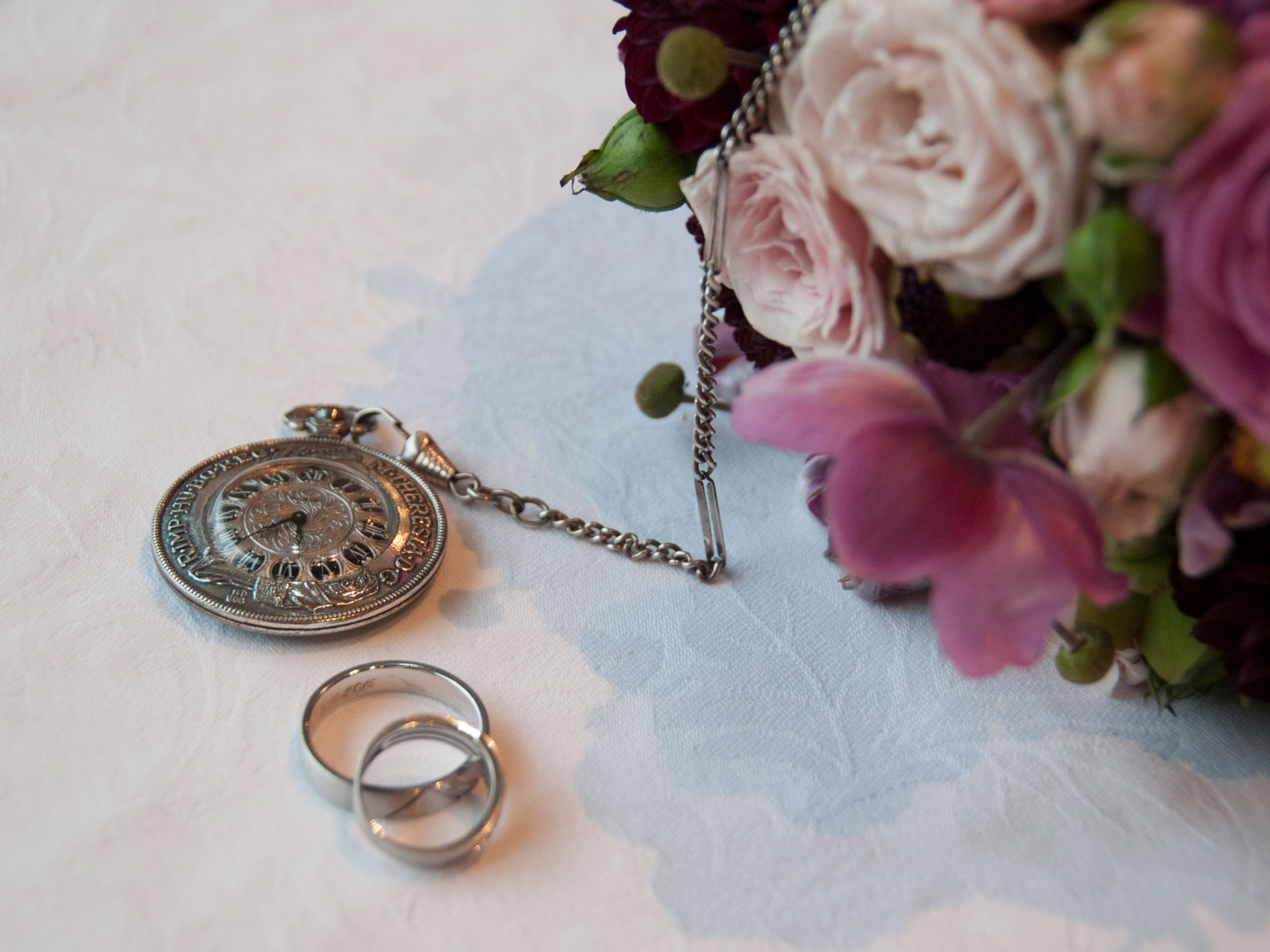 ein Stilleben mit den Eheringen, Brautstrauss und alter Taschenuhr