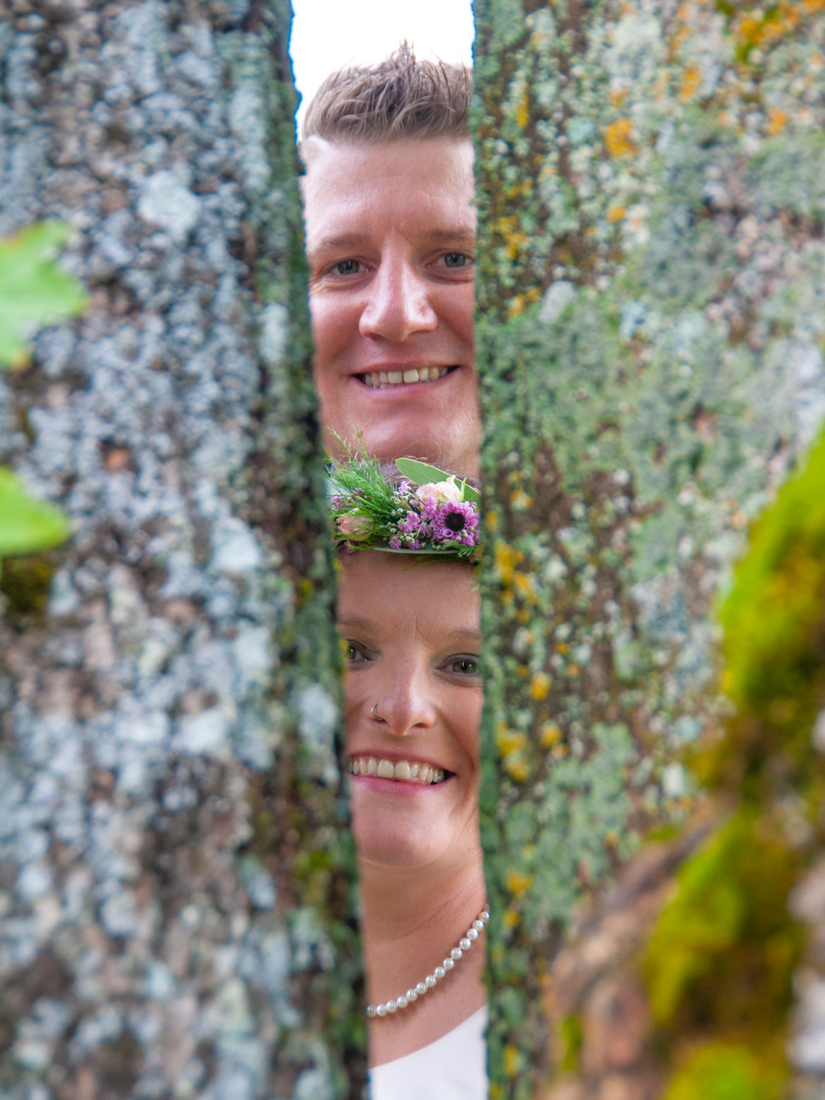 Das Hochzeitspaar schaut zwischen zwei Bäumen hindurch