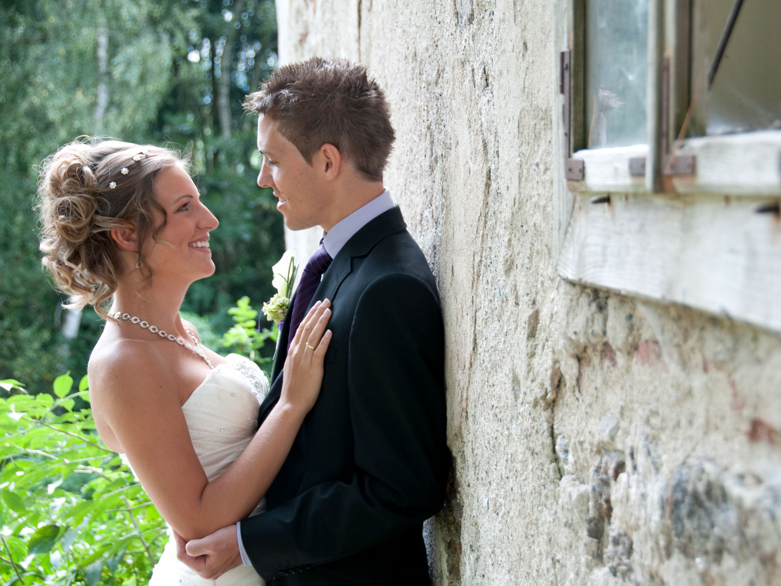 Das Hochzeitspaar steht an der Schlossmauer und sieht sich an