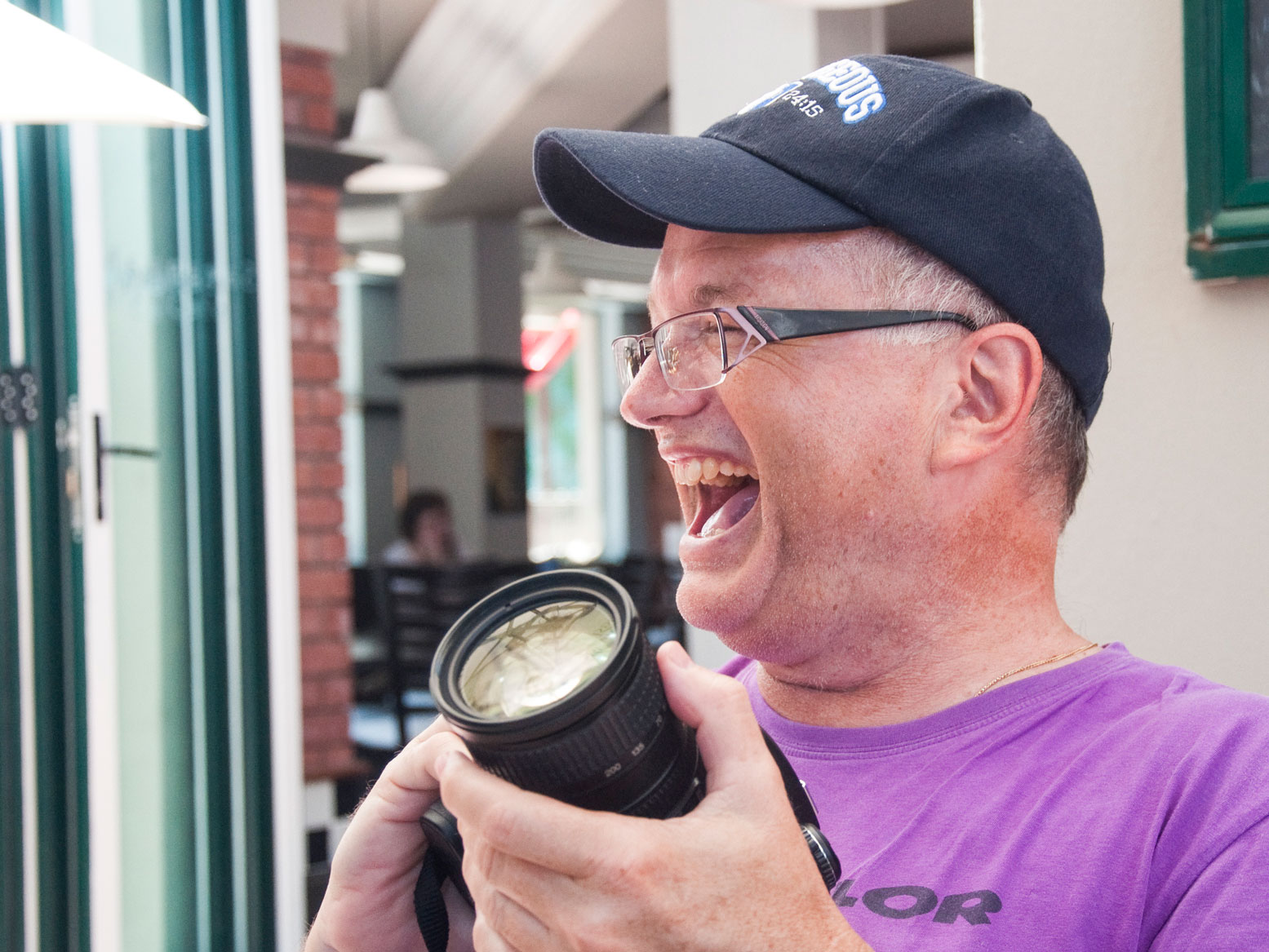herzhaftes Lachen des Fotografen mit der Kamera in der Hand