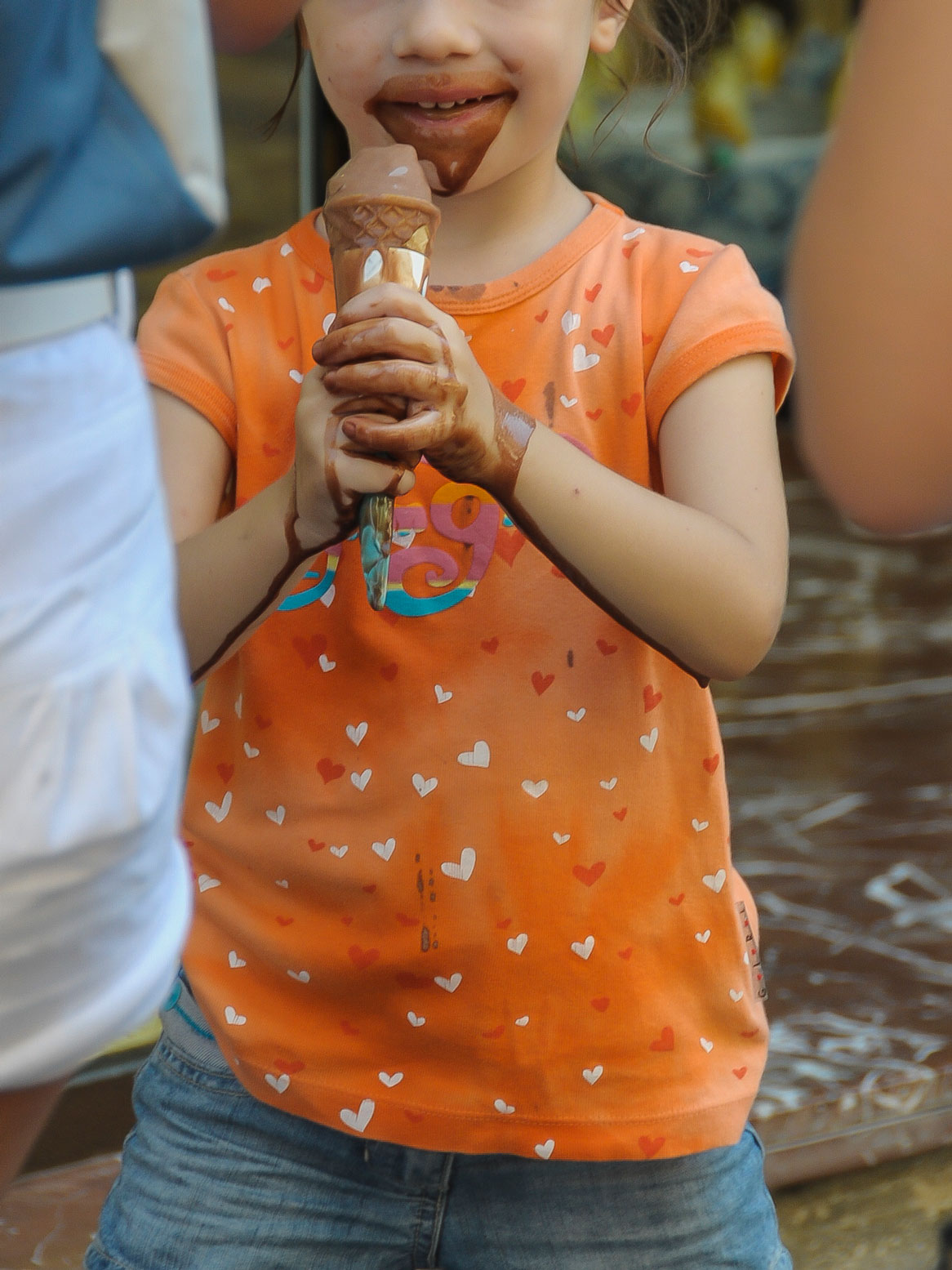 Ein vollbekleckertes Kind schleckt ein Eis