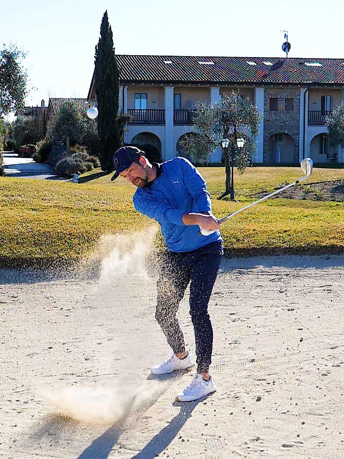 Bunkerschlag mit aufsprtzenden Sand und den Ball in der Luft