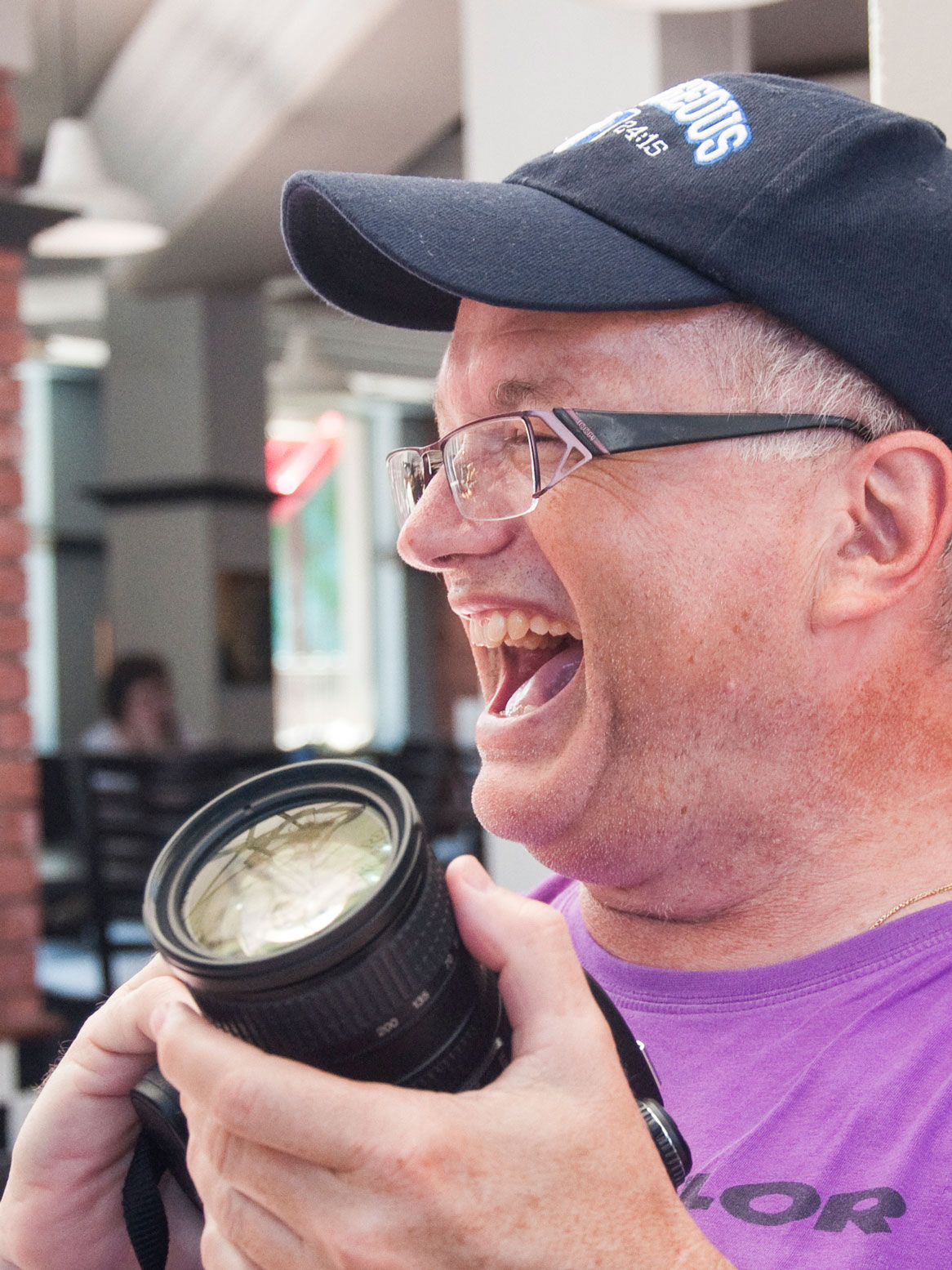 herzhaftes Lachen des Fotografen mit der Kamera in der Hand