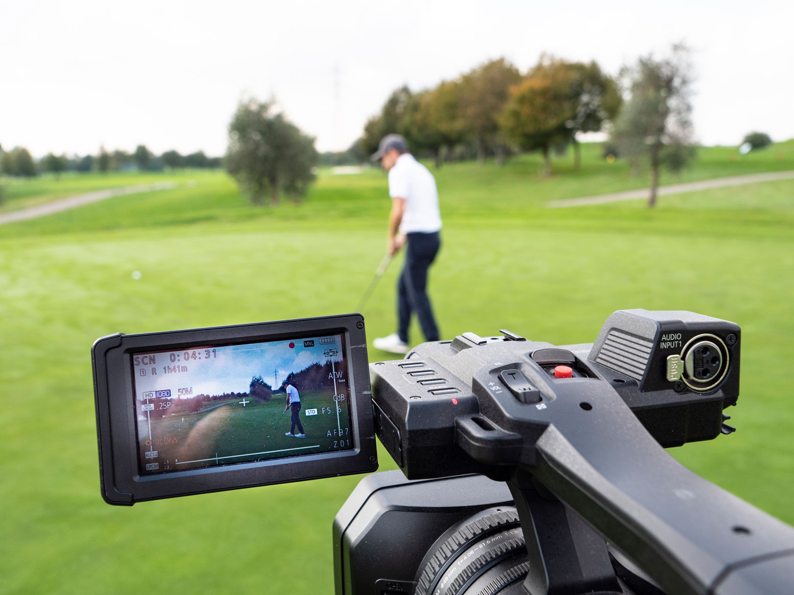 Golfpro wird gefilmt. Im Vordergrund steht die Kamera. Ein Making of Foto
